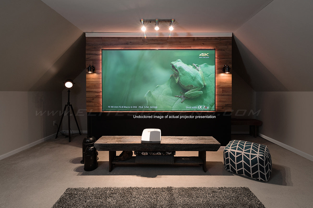 A home theater setup featuring a large projection screen with a image displayed, a table in front, and a ceiling light above.