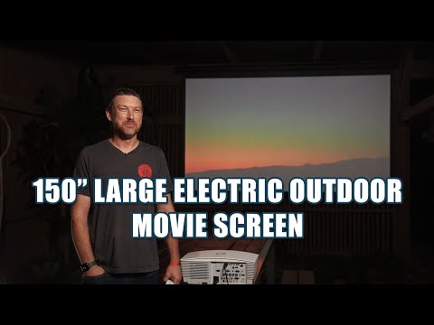 Man in a dark setting standing in front of a projector screen