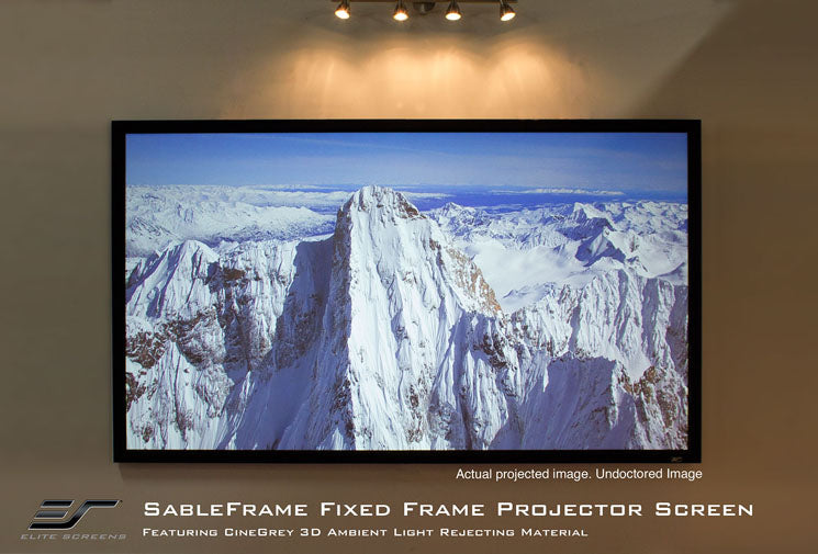 A projector screen displaying a mountain range, mounted on a wall with a black velvet frame.